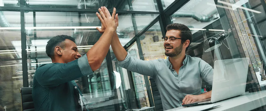 two businessmen giving each other high five - the most important marketing metric is conversions into sales